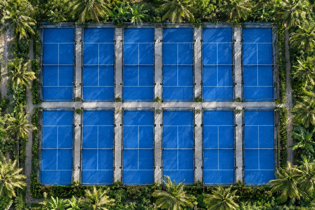 Vista aérea de doce pistas de pádel al aire libre entre vegetación tropical. Imagen ilustrativa generada con IA; no es una foto del hecho.