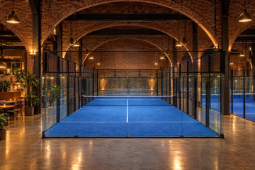 Pistas de pádel cubiertas bajo los arcos de ladrillo de un antiguo depósito ferroviario, con cafetería. Imagen ilustrativa generada con IA; no es una foto del hecho.